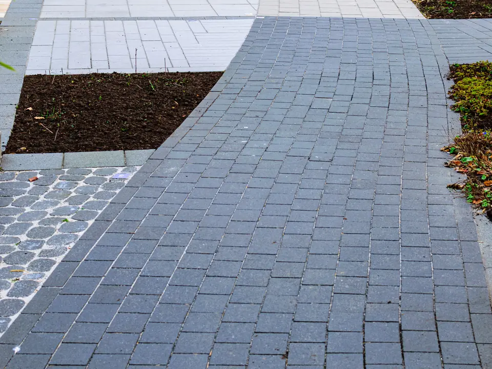 Geschwungene Pflasterfläche in einer modernen Gartenanlage.